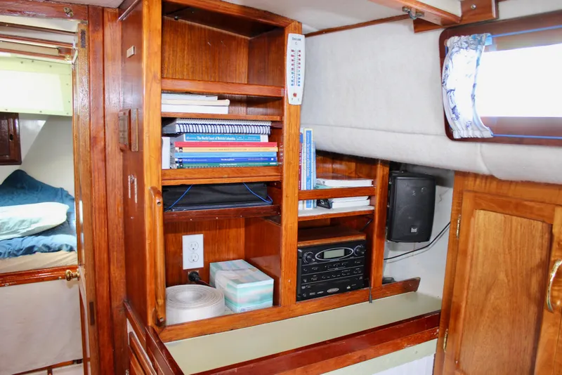 Slide: The Image of Interior of a 1975 Downeast 38 sailboat with wooden shelves and nautical decor. - 52