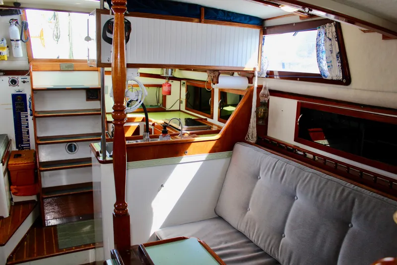 Slide: The Image of Interior of a 1975 Downeast 38 sailboat, featuring cozy seating and wooden accents. - 56