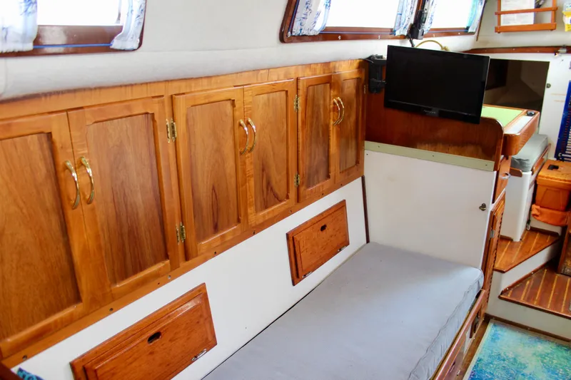 Slide: The Image of Interior of a 1975 Downeast 38 boat with wooden cabinets and a small TV. - 57