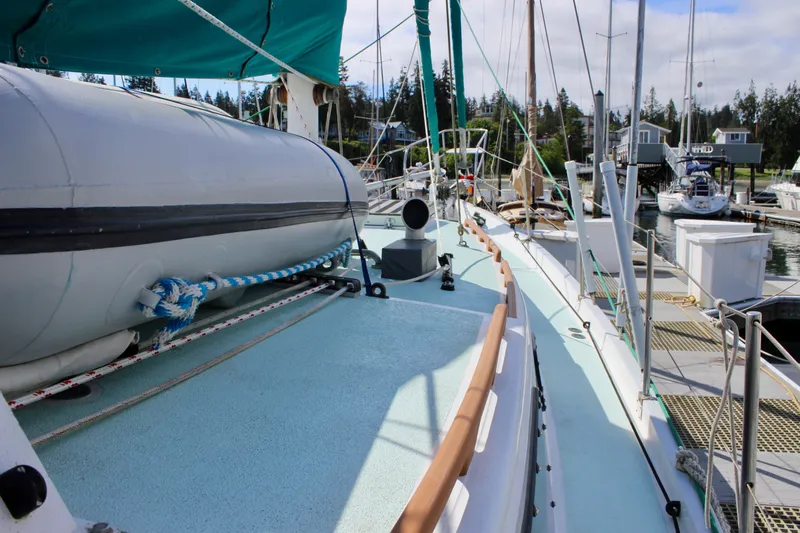 Slide: The Image of 1975 Downeast 38 sailboat docked, featuring deck view with lifeboat and marina background. - 6