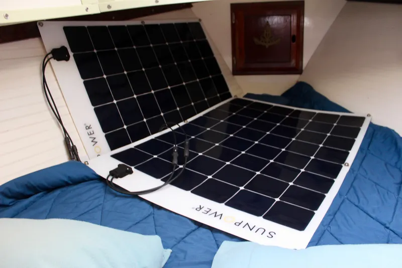 Slide: The Image of Flexible solar panels inside a 1975 Downeast 38 boat cabin, resting on a blue bedspread. - 70