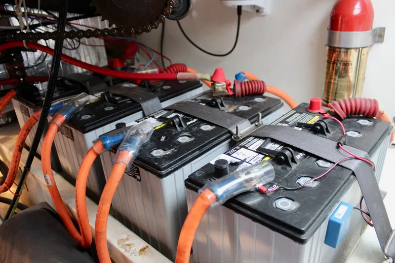 Slide: The Image of Battery setup in a 1975 Downeast 38 boat, featuring orange cables and fire extinguisher. - 76