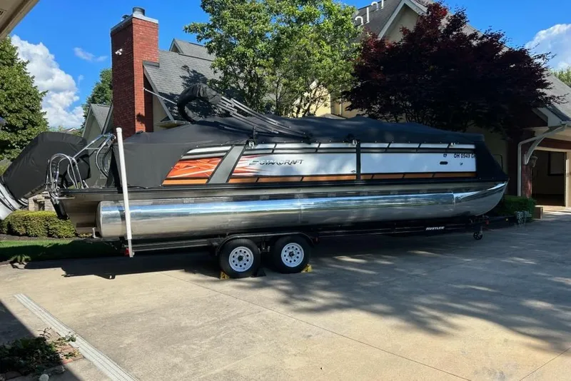 The Image of 2022 Starcraft CX 25 DL BAR pontoon boat on trailer in residential driveway. - 1