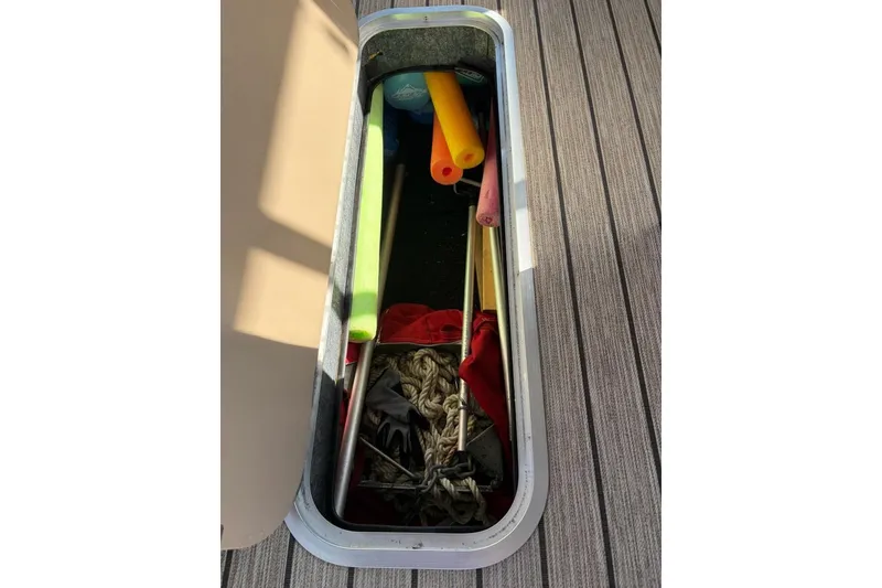 Slide: The Image of Storage compartment on 2022 Starcraft CX 25 DL BAR boat with pool noodles and rope. - 21