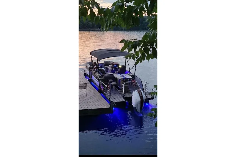 Slide: The Image of 2022 Starcraft CX 25 DL BAR pontoon boat docked at sunset with blue LED lights. - 25