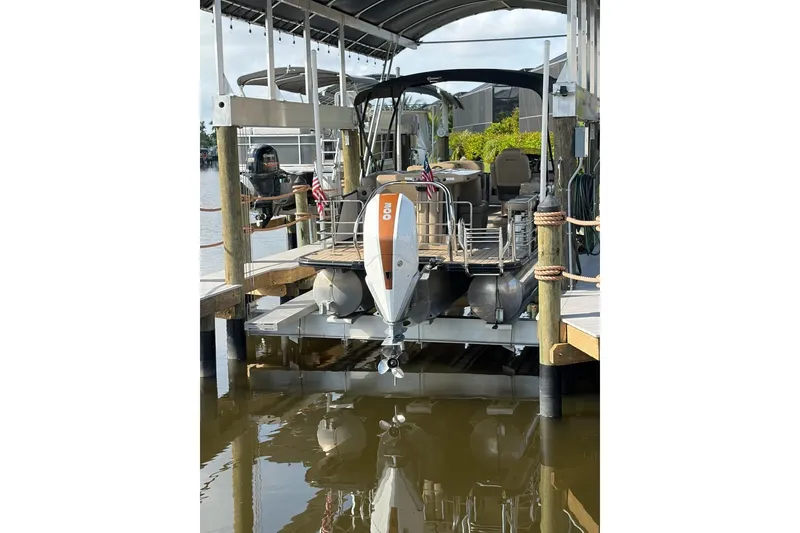 Slide: The Image of 2022 Starcraft CX 25 DL BAR pontoon boat docked on a lift by the water. - 6