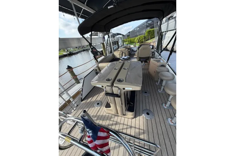 Slide: The Image of 2022 Starcraft CX 25 DL BAR pontoon boat interior with seating and table, docked by water. - 8