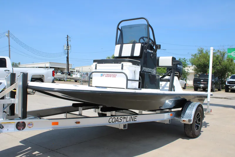 Slide: The Image of 2026 Freedom Boats Chiquita on trailer, parked outdoors under clear blue sky. - 3