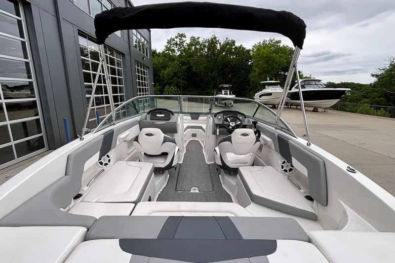 Slide: The Image of 2021 Chaparral 23 SSi boat interior with seating and steering wheel, docked near other boats. - 10