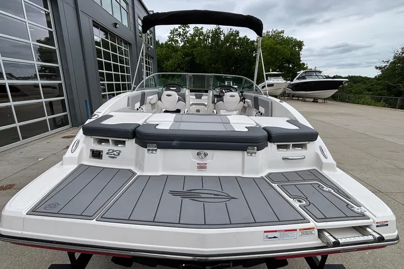 Slide: The Image of 2021 Chaparral 23 SSi boat with sleek design, docked outdoors near modern building. - 4