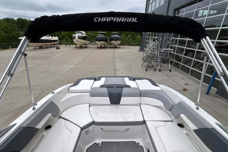 Slide: The Image of 2021 Chaparral 23 SSi boat interior with seating and canopy, parked near other boats. - 43