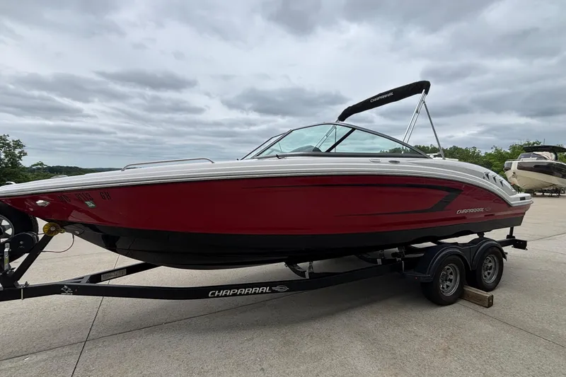Slide: The Image of 2021 Chaparral 23 SSi boat with red and black hull on a trailer, under cloudy skies. - 45