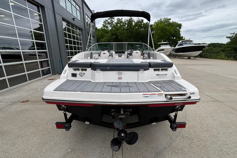 Slide: The Image of 2021 Chaparral 23 SSi boat, rear view, docked near modern building and trees. - 47