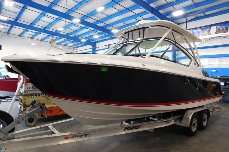The Image of 2022 Pursuit DC 266 Dual Console boat on trailer in indoor showroom. - 1