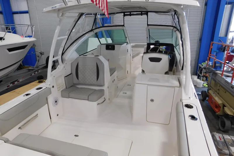 Slide: The Image of 2022 Pursuit DC 266 Dual Console boat interior with seating and helm in a showroom. - 12