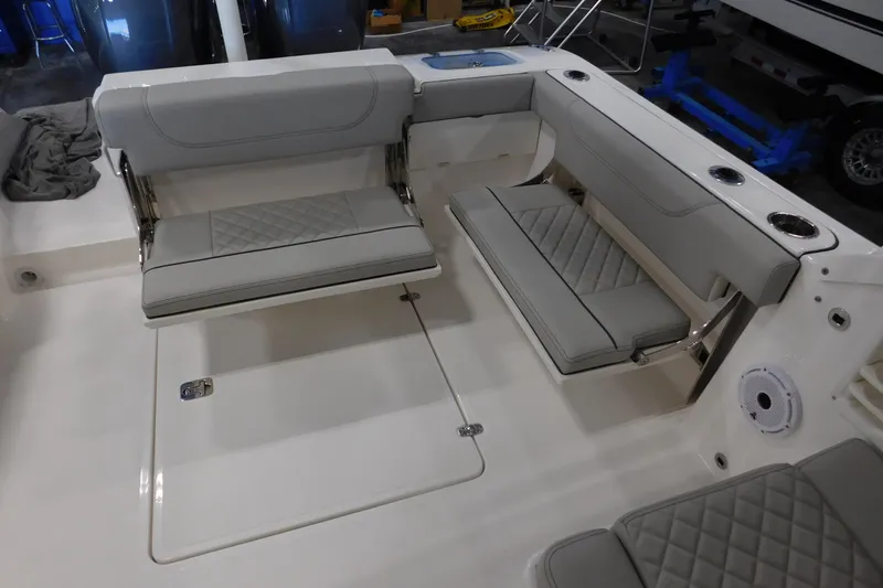 Slide: The Image of 2022 Pursuit DC 266 Dual Console boat interior with gray cushioned seating and storage compartments. - 16