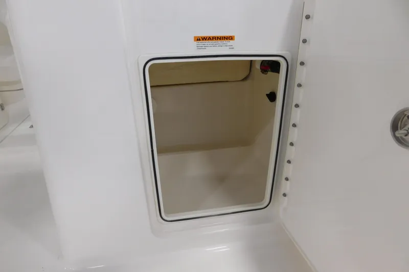 Slide: The Image of Storage compartment on a 2022 Pursuit DC 266 Dual Console boat, featuring a warning label. - 18