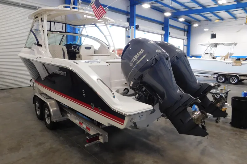 Slide: The Image of 2022 Pursuit DC 266 Dual Console boat with twin Yamaha engines in a showroom. - 2