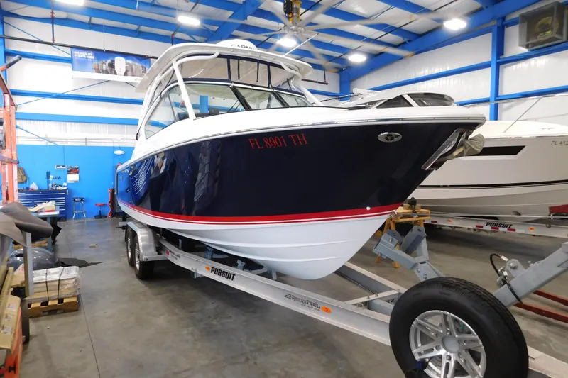Slide: The Image of 2022 Pursuit DC 266 Dual Console boat on trailer in a spacious indoor facility. - 4