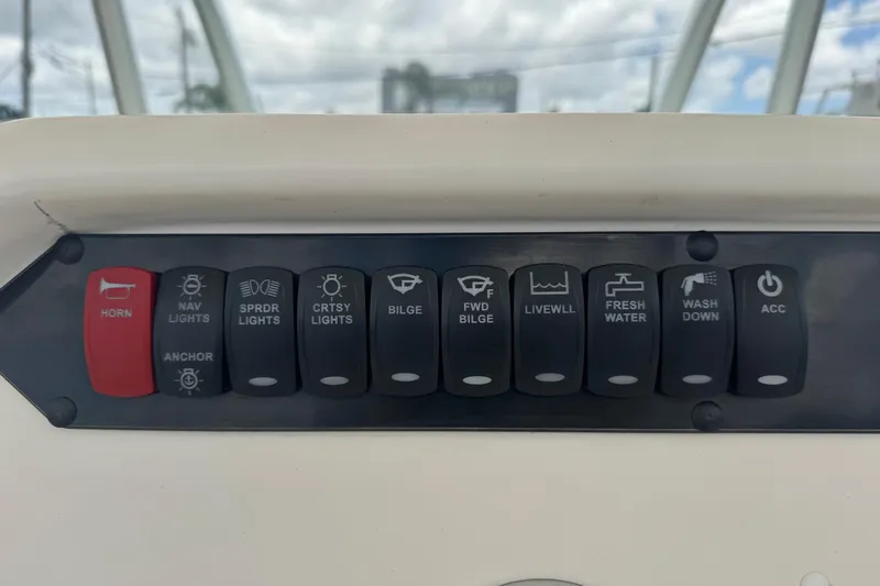Slide: The Image of Control panel of 2023 Sailfish 242 CC boat with labeled switches for various functions. - 13