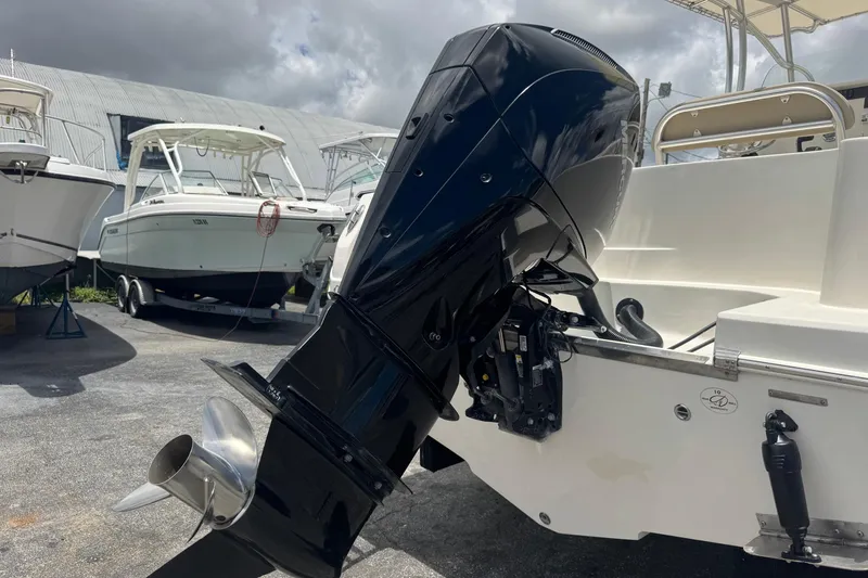 Slide: The Image of 2023 Sailfish 242 CC boat with powerful outboard motor in a marina setting. - 43
