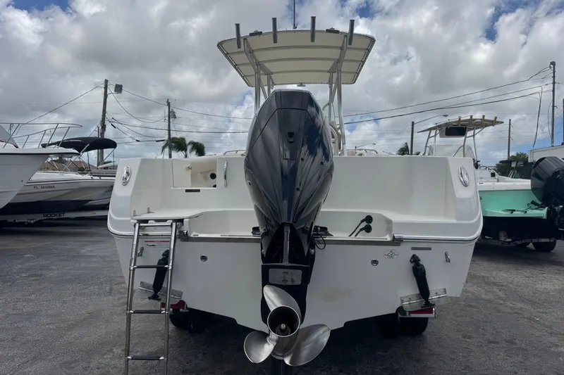 Slide: The Image of 2023 Sailfish 242 CC boat with outboard motor and ladder, parked outdoors. - 5