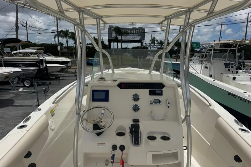 Slide: The Image of 2023 Sailfish 242 CC boat dashboard with steering wheel and controls, docked outdoors. - 6