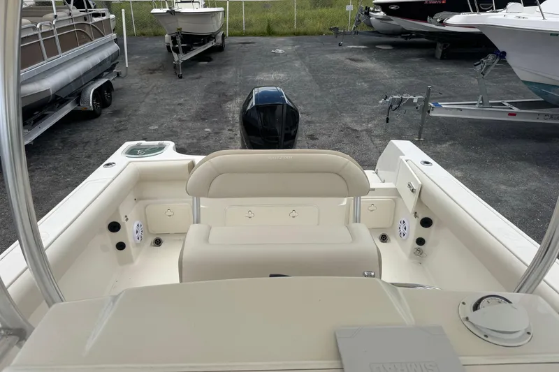 Slide: The Image of 2023 Sailfish 242 CC boat interior with seating and motor, parked in a marina. - 9
