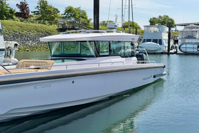 Slide: The Image of 2020 Axopar 37 XC Cross Cabin boat docked in a marina, surrounded by other vessels. - 7