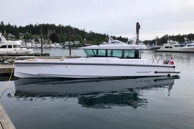 Slide: The Image of 2020 Axopar 37 XC Cross Cabin boat docked in a marina, surrounded by water and other boats. - 5