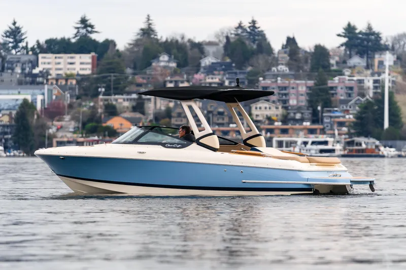 Slide: The Image of 2025 Chris-Craft Sportster 25 boat cruising on a scenic lake with urban backdrop. - 3