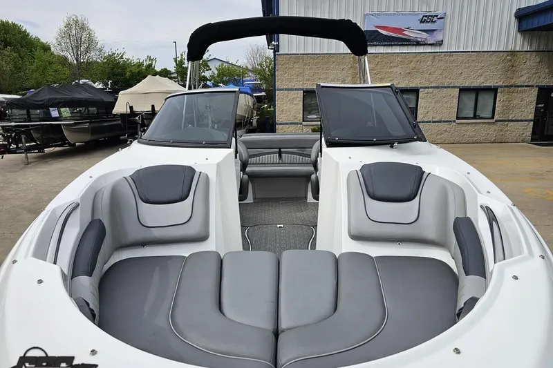 Slide: The Image of 2020 Rinker 19QX BR boat with sleek seating, displayed outdoors at a dealership. - 24