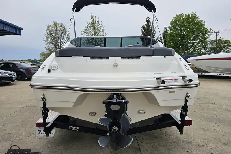 Slide: The Image of 2020 Rinker 19QX BR boat, rear view, parked on concrete with trees in background. - 38