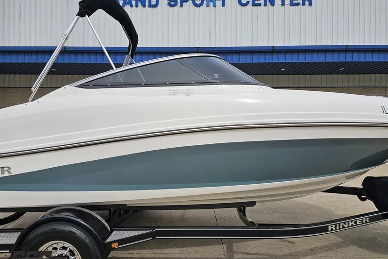 Slide: The Image of 2020 Rinker 19QX BR boat on trailer, parked outside a sports center. - 5