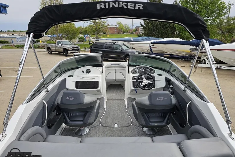 Slide: The Image of 2020 Rinker 19QX BR boat interior with seating and steering wheel, parked outdoors. - 51