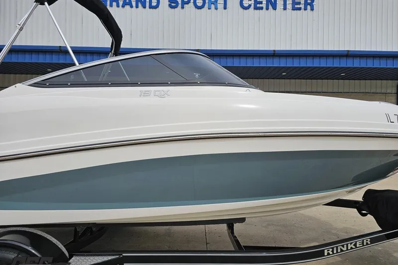 Slide: The Image of 2020 Rinker 19QX BR boat on trailer outside a sports center. - 6