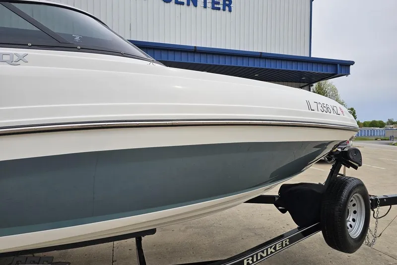Slide: The Image of 2020 Rinker 19QX BR boat on trailer, parked outside a building. - 7
