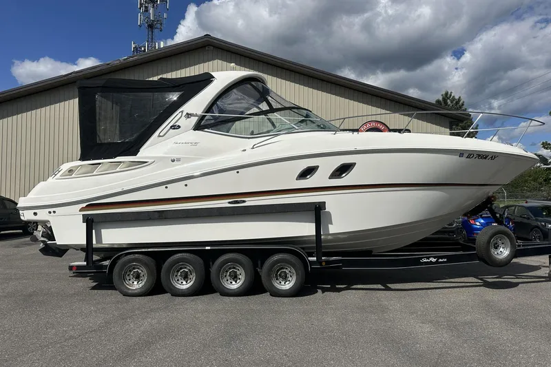Slide: The Image of 2009 Sea Ray Sundancer 310 boat on trailer, parked outdoors under cloudy sky. - 2