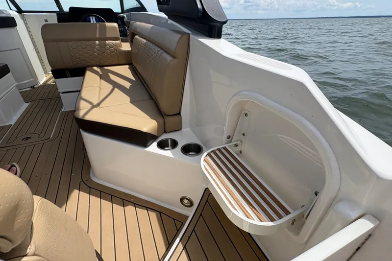 Slide: The Image of 2021 Sea Ray SDX 270 boat interior with tan seating and wooden deck, on open water. - 20