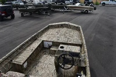 Slide: The Image of 2025 Lowe Roughneck 1860SC boat with camouflage design, parked in a lot with trailers. - 7