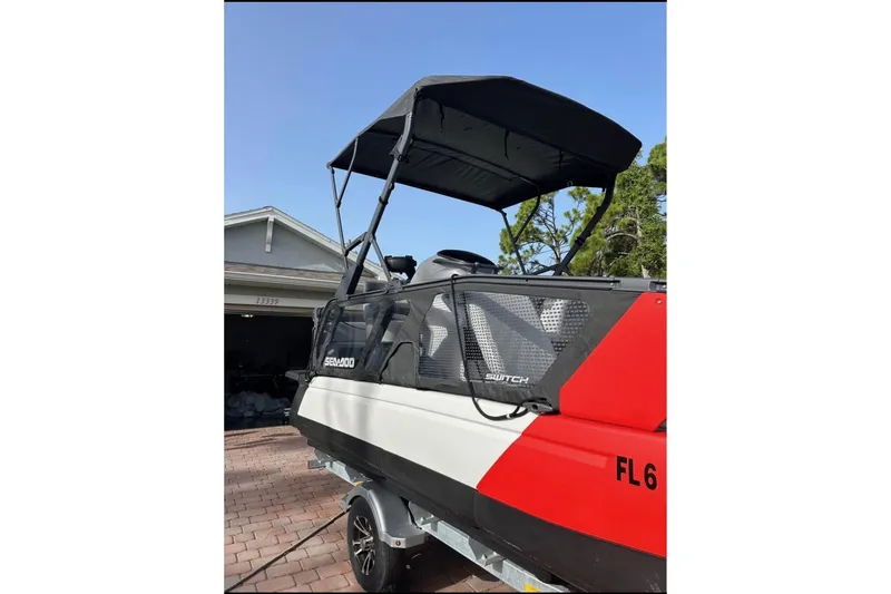 Slide: The Image of 2024 Sea-Doo Switch Cruise 18 pontoon boat with canopy, parked on a driveway. - 10