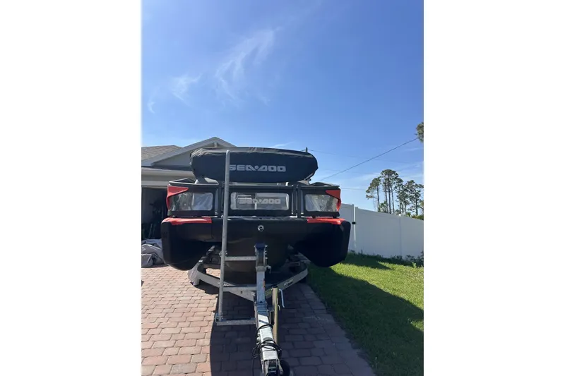 Slide: The Image of 2024 Sea-Doo Switch Cruise 18 on trailer, parked in driveway under clear blue sky. - 11