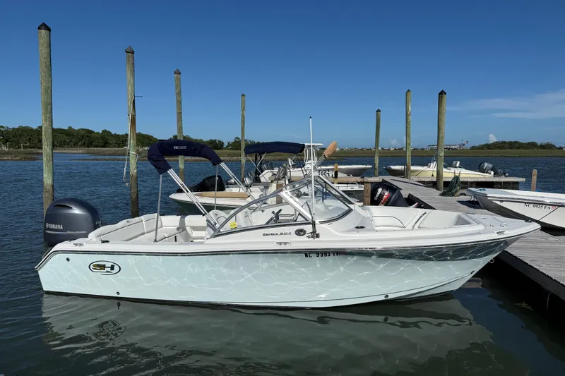 Slide: The Image of 2017 Sea Hunt Escape 211 LE boat docked by the water on a sunny day. - 2
