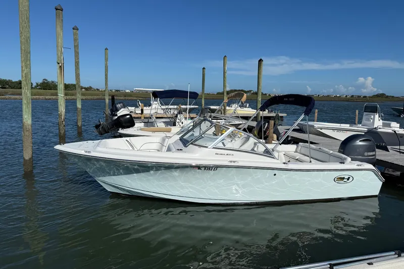 Slide: The Image of 2017 Sea Hunt Escape 211 LE boat docked in a marina under clear blue skies. - 4