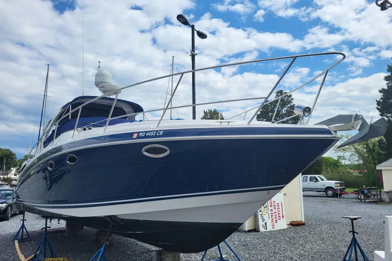 Slide: The Image of 2006 Four Winds Vista 348 boat on stands, blue hull, cloudy sky background. - 1