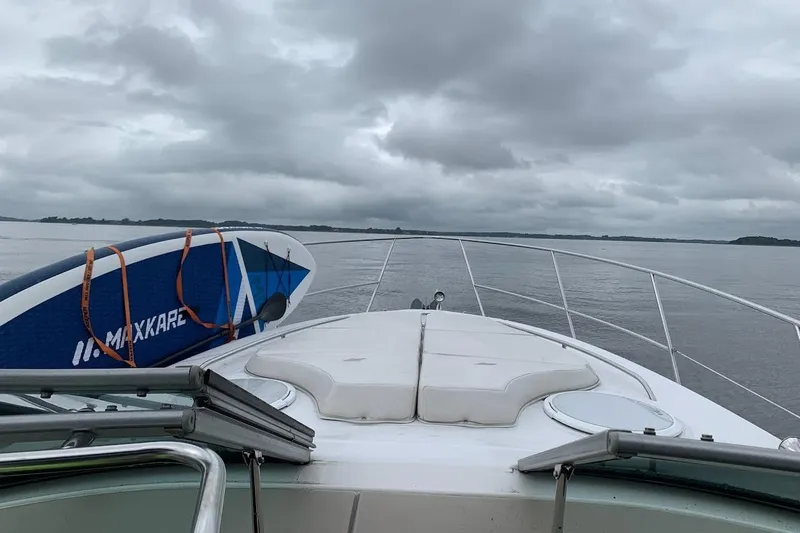Slide: The Image of 2006 Four Winds Vista 348 boat with paddleboard on deck, cruising under cloudy skies. - 26