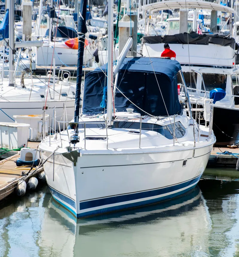 Slide: The Image of 2005 Hunter 45 CC sailboat docked in a marina, surrounded by other boats. - 2