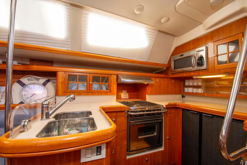 Slide: The Image of 2005 Hunter 45 CC yacht kitchen with wood cabinetry, stainless steel sink, stove, and microwave. - 29