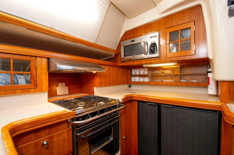 Slide: The Image of 2005 Hunter 45 CC yacht kitchen with stove, microwave, and wooden cabinetry. - 30