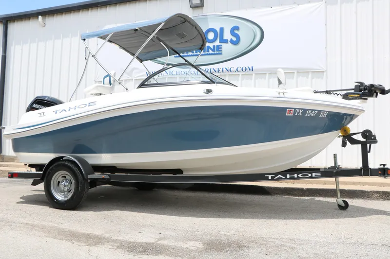 The Image of 2018 Tahoe 450 TF boat on trailer, blue and white design, parked outdoors. - 1
